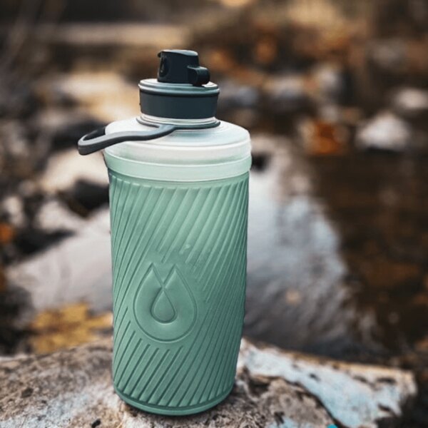 Hydrapak skladacia fľaša a vodný filter používané pri prírodnom zdroji. Outdoor vybavenie na hydratáciu. Foto: Rigad