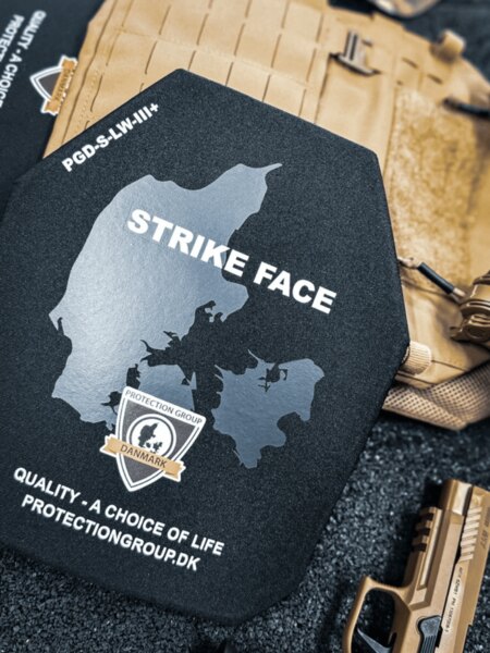 Tvrdý balistický plát so stranou STRIKE FACE (PGD); v pozadí plate carrier a služobná pištoľ, detail pred vložením do nosiča.