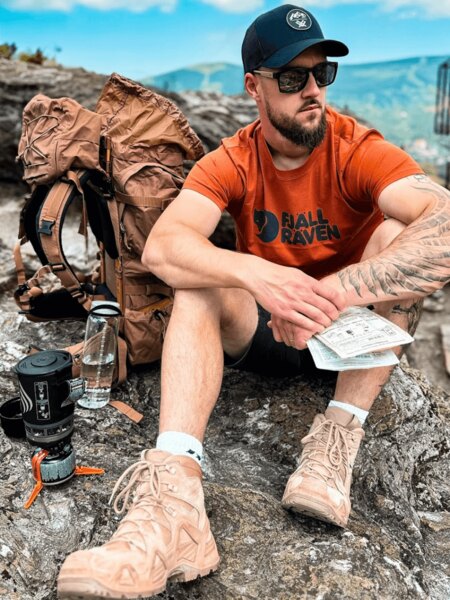 Outdoorový turista s batohom, šiltovkou a vodou ako ochrana pred úpalom. Foto: Rigad