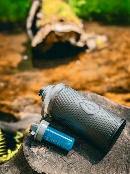 Fľaša Flux HydraPak s filtrom Cap položená na pni v prírode, ideálna na cestovanie a outdoor. Foto: Rigad