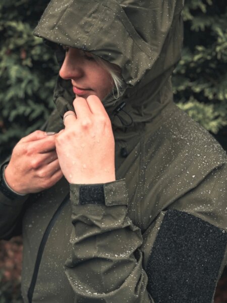 Žena v nepremokavej bunde Helikon-Tex Squall s kvapkami vody na kapucni a rukávoch.