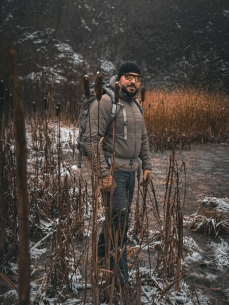 Muž v zimnom outdoorovom oblečení s batohom v zasneženom mokradi.