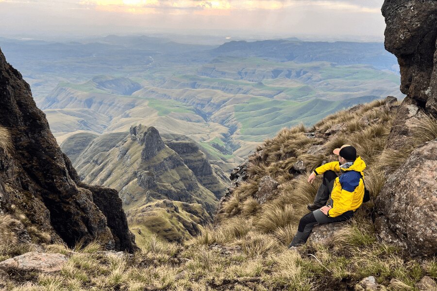 Muž v žltej outdoorovej bunde sedí na svahu v Dračích horách v Afrike. Foto: Archív autora