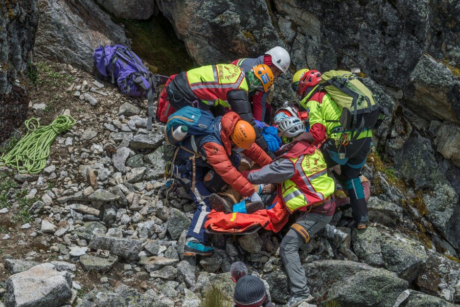 Horské záchranné družstvo stabilizuje zraneného počas evakuácie v kamenistom teréne. Foto: https://www.pexels.com/cs-cz/foto/skupina-zachranaru-zachranujicich-zranenou-osobu-na-rocky-mountainside-9424563/