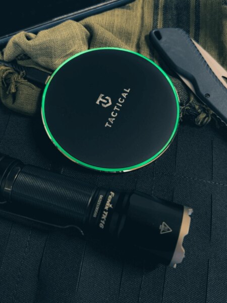 Bezdrôtová nabíjačka Base Plug Tactical<sup>&reg;</sup> so svietiacim LED krúžkom položená na taktickom vybavení – Qi 15 W, protišmykový povrch. Foto: Rigad
