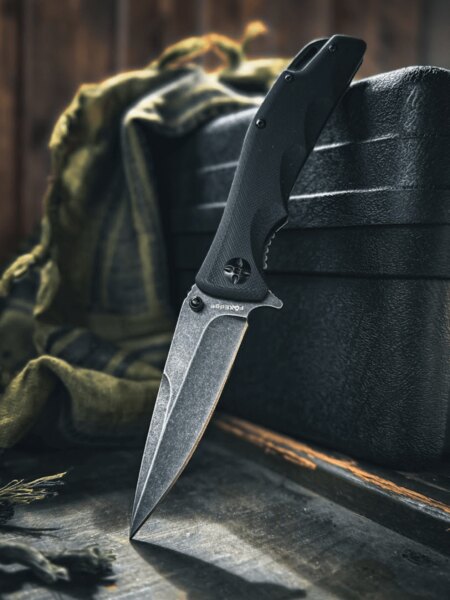 Zatvárací nôž Fox Edge<sup>&reg;</sup> s čepeľou v stonewashed úprave opretý o čierny kufor. Foto: Rigad
