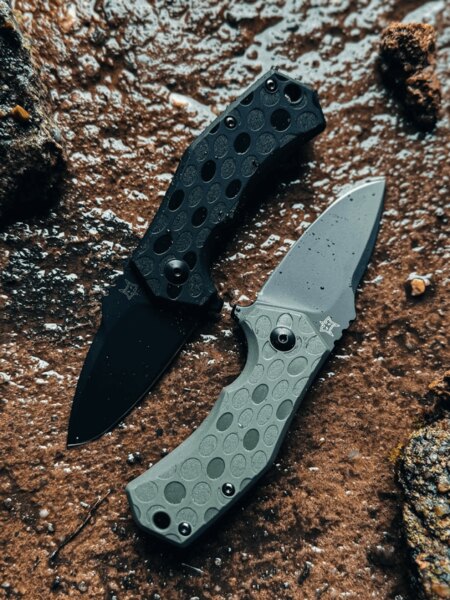 Dvojica zatváracích nožov Fox Knives<sup>&reg;</sup> s čiernou a zelenou rúčkou v outdoorovom prostredí. Foto: Rigad