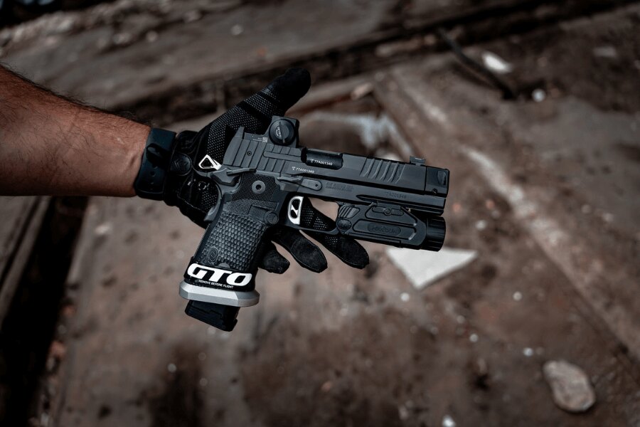 Pištoľ plnej veľkosti s kolimátorom a podvesným svietidlom pri držaní obojručným úchytom – Foto: Rigad