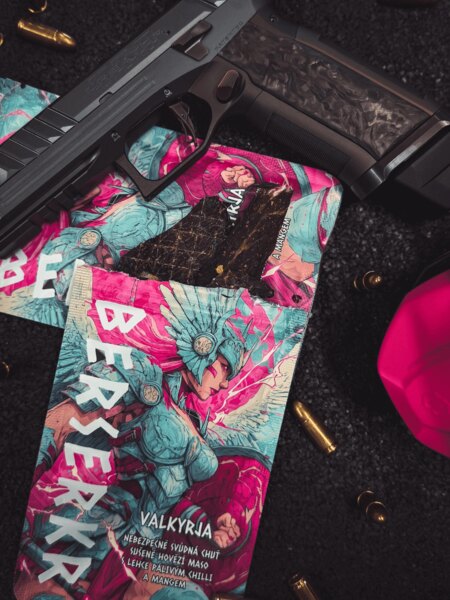 Balenie sušeného mäsa Berserkr VALKYRJA Mango a Chilli s viditeľným kúskom jerky, umiestnené vedľa zbrane a streliva. Foto: Rigad