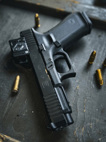 Glock 47 s kolimátorom Aimpoint COA na A-CUT, detail pištole s nábojmi na stole. Foto: Rigad