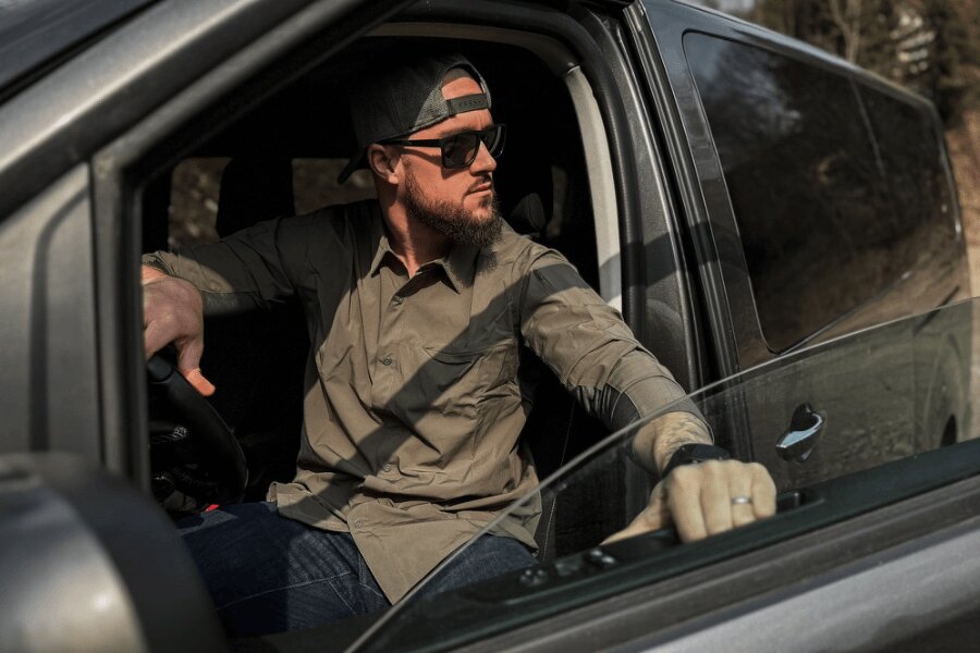 Muž v košeli Vertx sedí v aute a sleduje okolie. Foto: Rigad