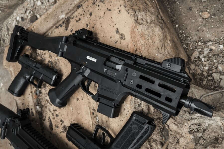 Moderný samopal CZ Scorpion EVO 3 s kolimátorom a teleskopickou pažbou položený na zemi vedľa pištolí a zásobníkov. Foto: Rigad