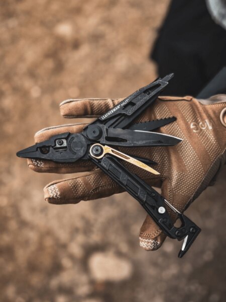 Multitool Leatherman MUT rozložený na dlani v taktickej rukavici.