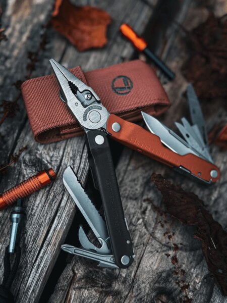 Multifunkčný nástroj Leatherman Rebar s rozloženými kliešťami a vysunutými nástrojmi na drevenom povrchu.