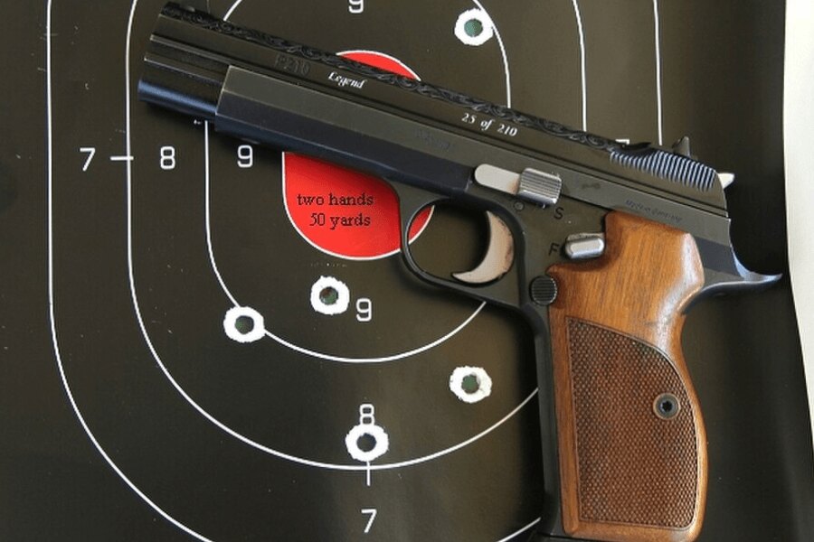 Pištoľ SIG P210 položená pred streleckým terčom.