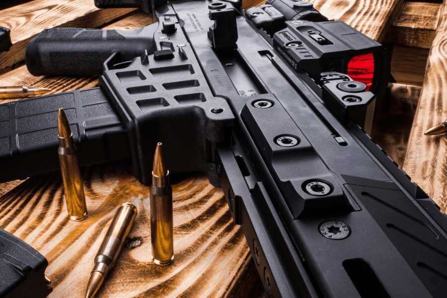 Detail samonabíjacej pušky CZ BREN 2 s kolimátorom na drevenom stole.