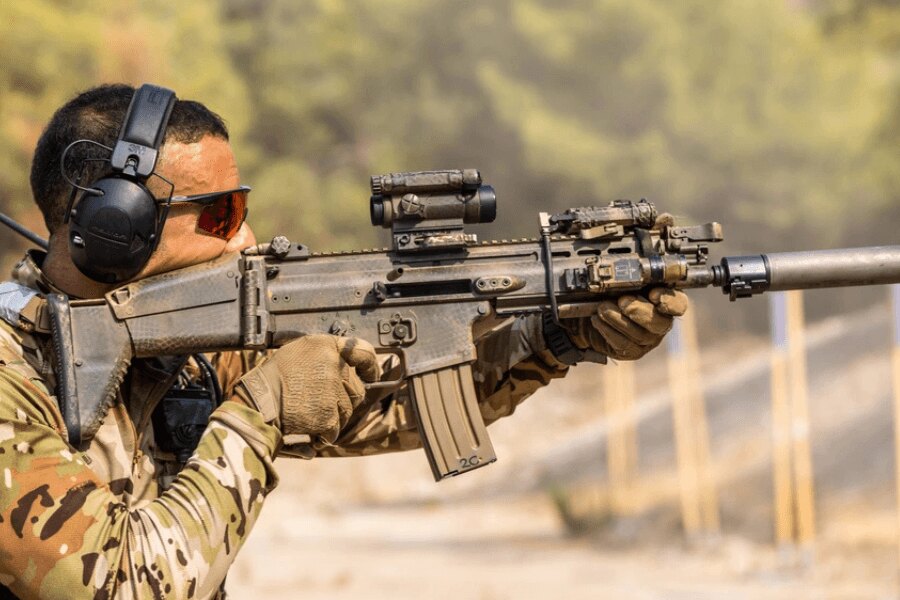 Strelec s puškou FN SCAR vybavenou kolimátorom, svietidlom a tlmičom.