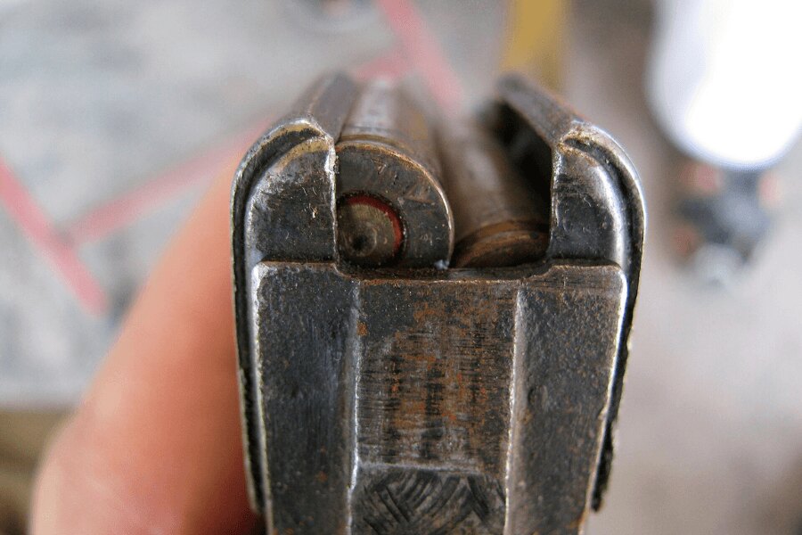 Detail hornej časti opotrebovaného oceľového zásobníka AK-47 s nábojmi kalibru 7,62 × 39 mm.
