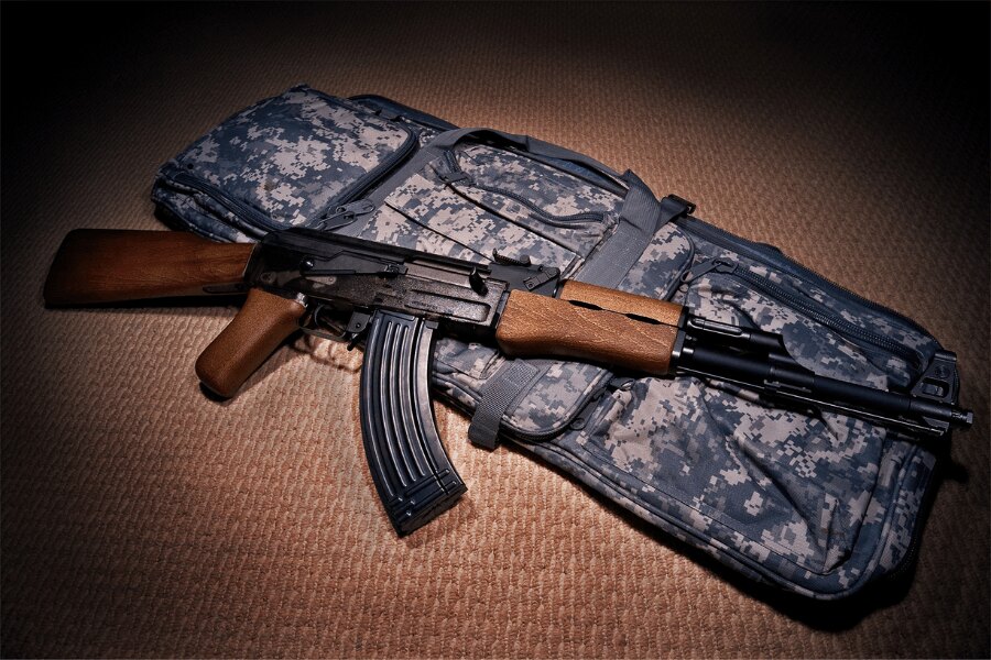 Airsoftová replika pušky AK-47 od G&G Armament položená na polstrovanom zbraňovom puzdre.