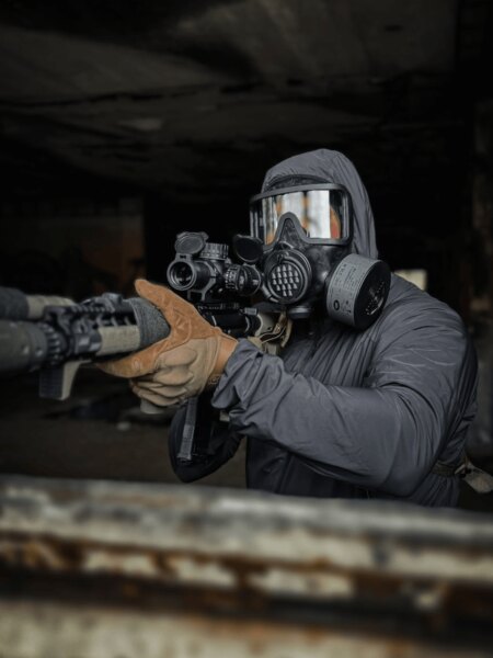 Strelec v celotvárovej ochrannej maske AVEC s filtrom pri mierení puškou.