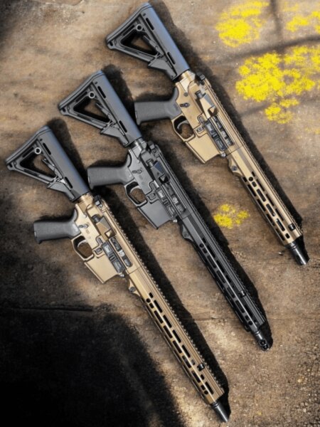 Detail čiernej pušky AR-15 s otvoreným krytom vyhadzovacieho okna medzi dvoma piestovými puškami.