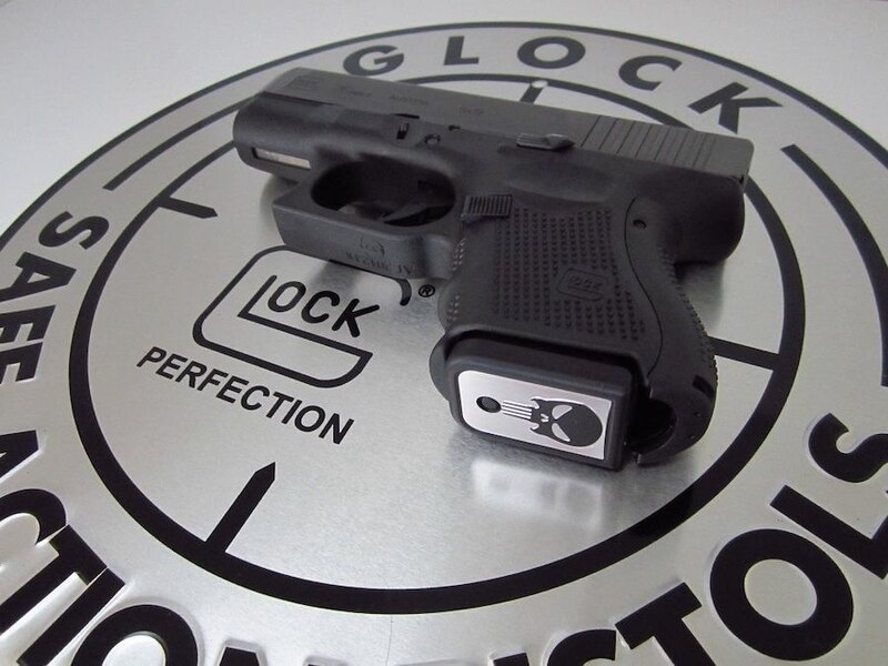 Pištoľ Glock položená na striebornom podklade