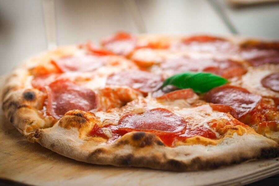 Salámová pizza na drevenom tanieri.