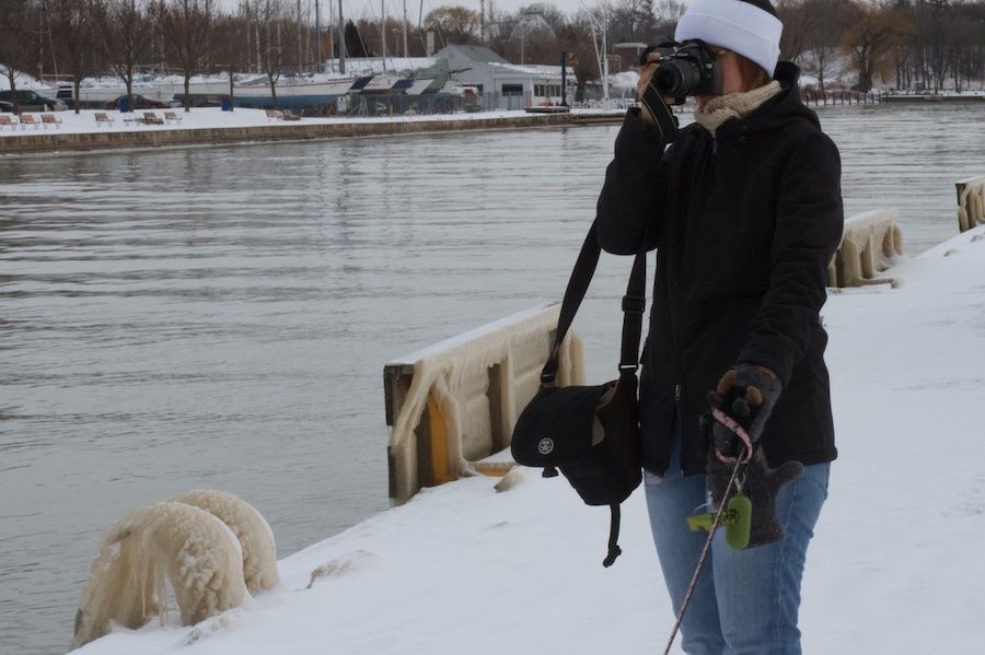 Žena stojaca pri vode s vodítkom a s fotoaparátom